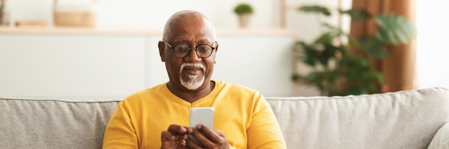Elderly man on couch looking at phone