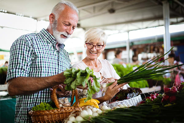 A senior couple shopping for vegetables at a farmers market